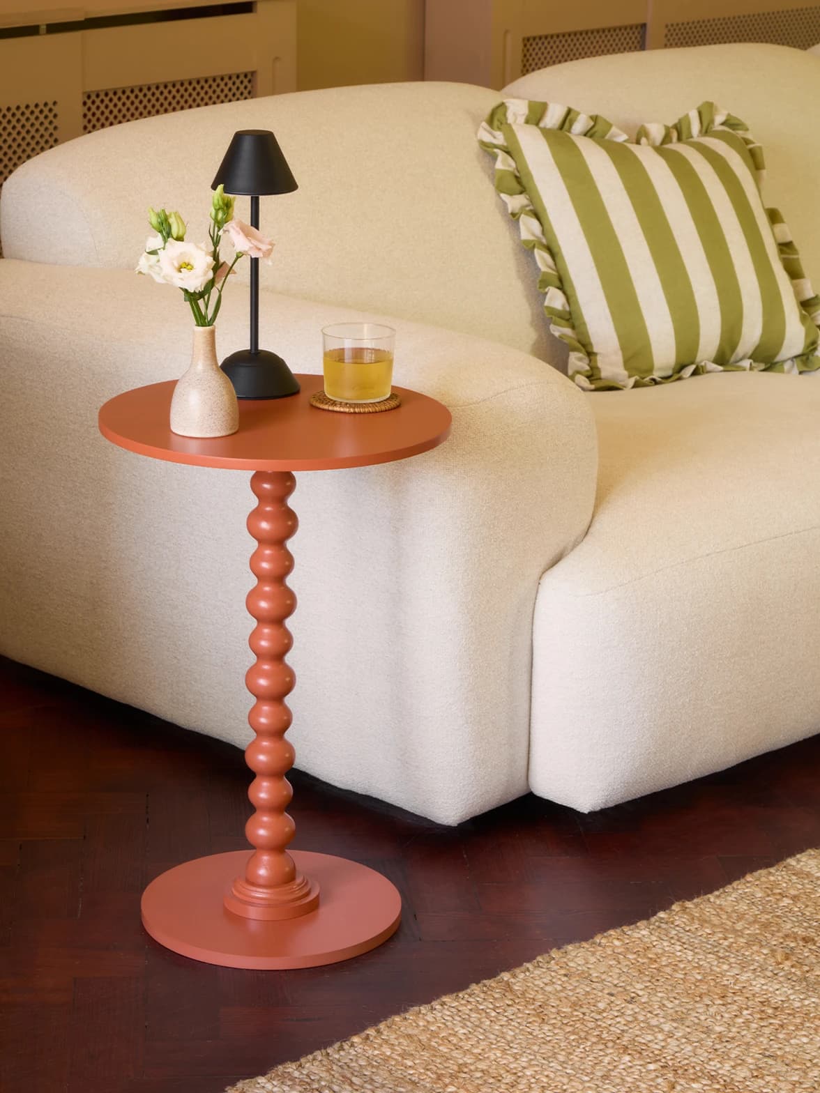 A bobble side table with rechargeable lamp placed next to a white sofa
