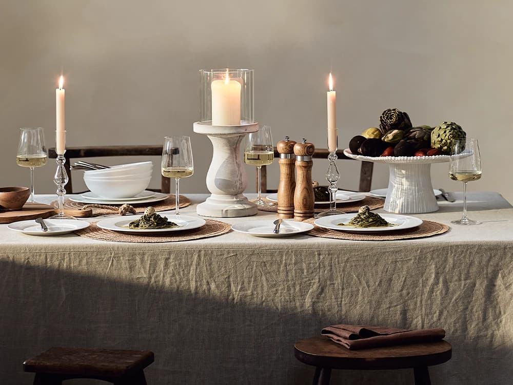 A minimal warm tablescape set with white crockery, glassware and candlesticks