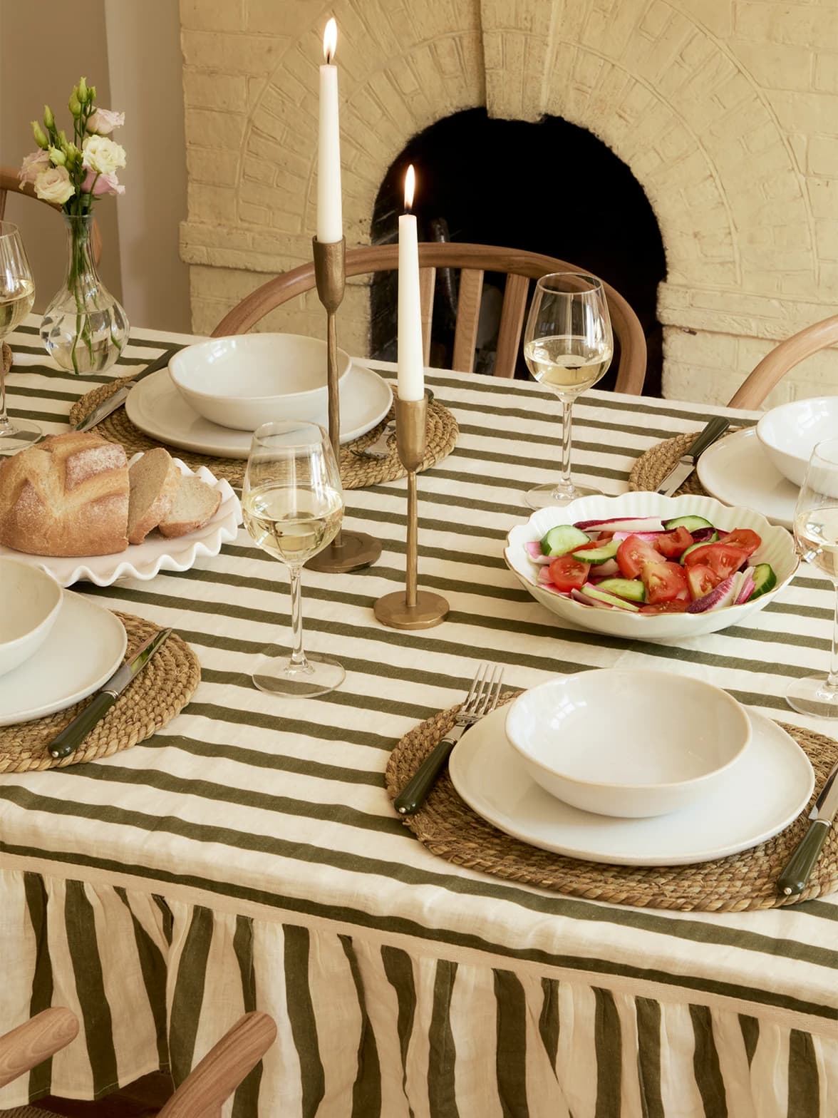 A table set with elegant glassware and crockery placed on seagrass placemats and striped tablecloth