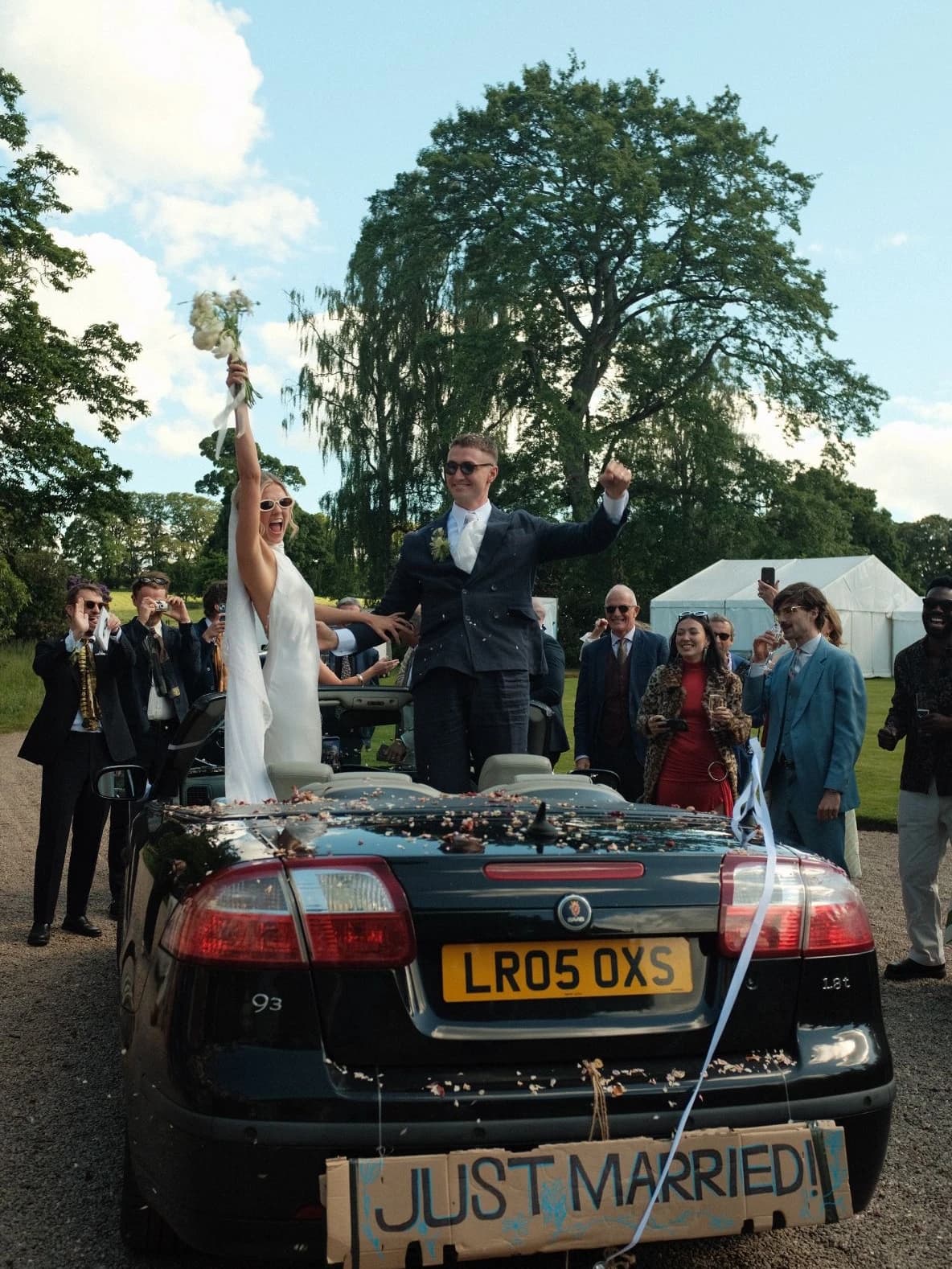 Newlyweds celebrating in their open-top car with a Just Married sign as guests cheer at Middleton House in Scotland