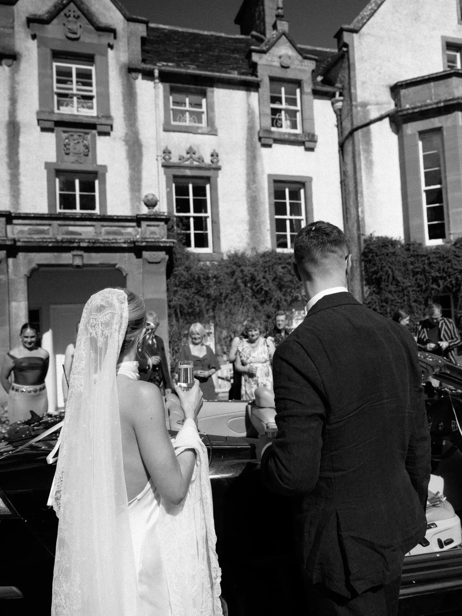 Bride in a vintage silk veil and groom arriving at Middleton House as guests gather outside for their festival wedding in Scotland